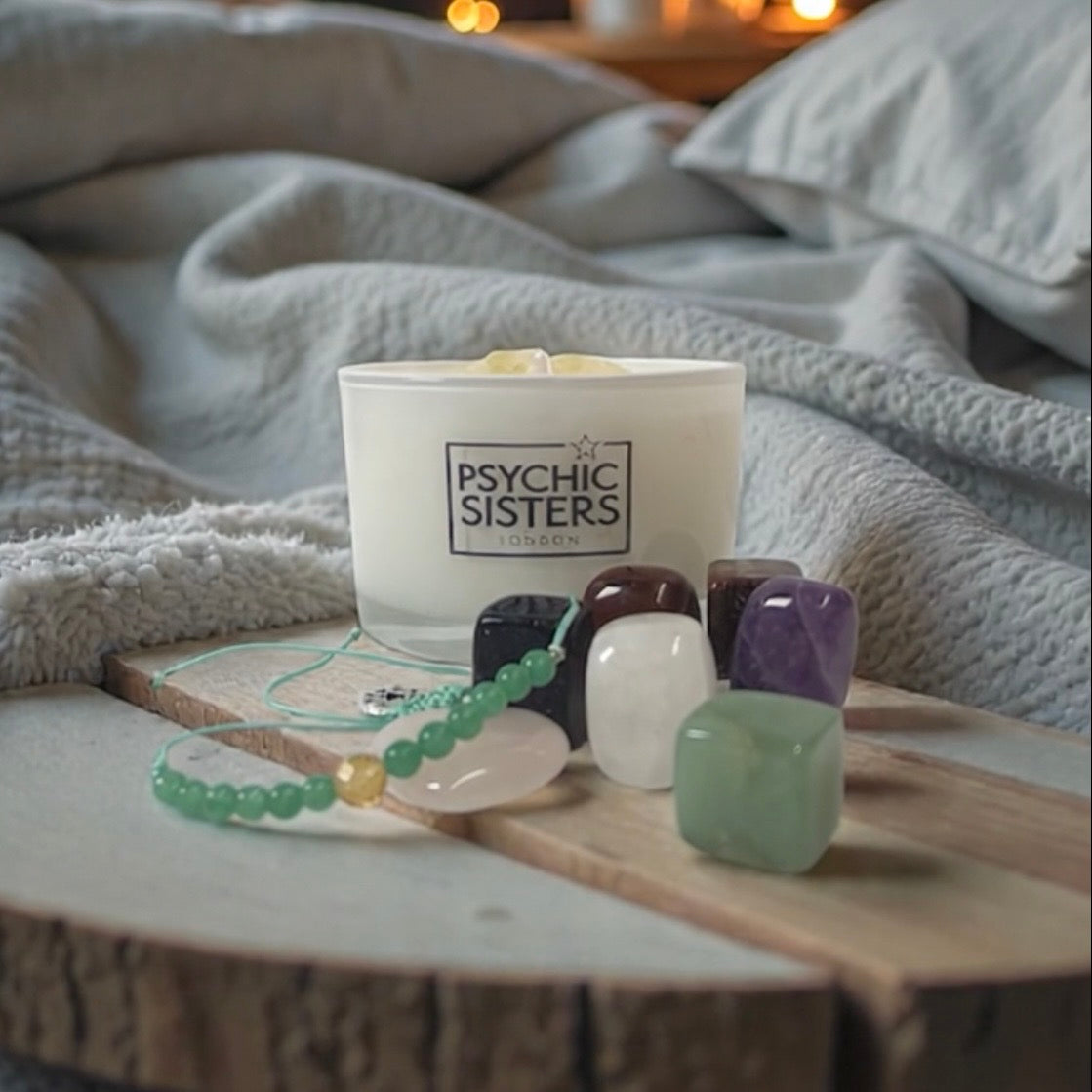 Monthly Gift Box featuring a candle and assorted crystals on a cozy blanket.
