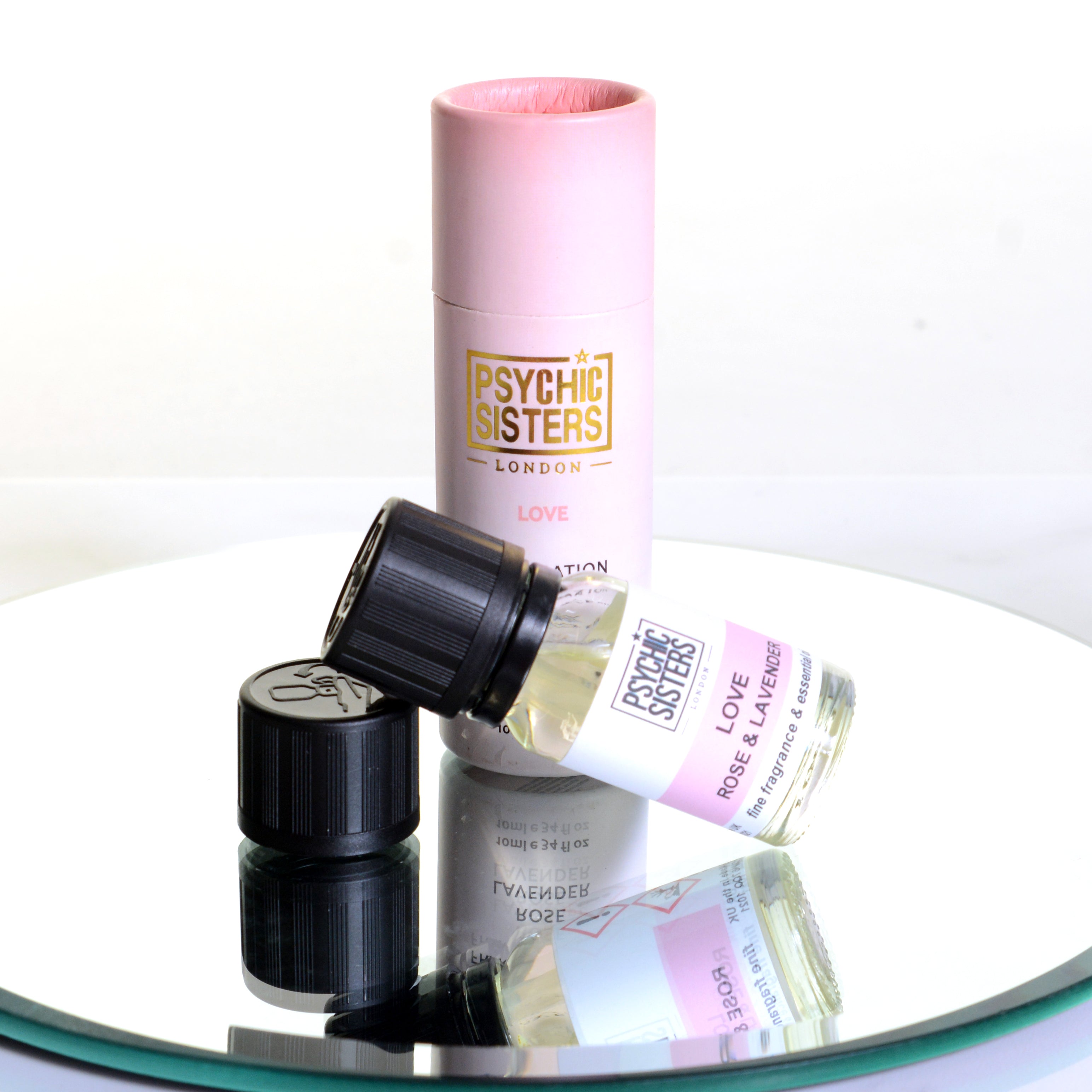 LOVE OIL by Psychic Sisters, featuring essential oil bottle and packaging on a reflective surface.