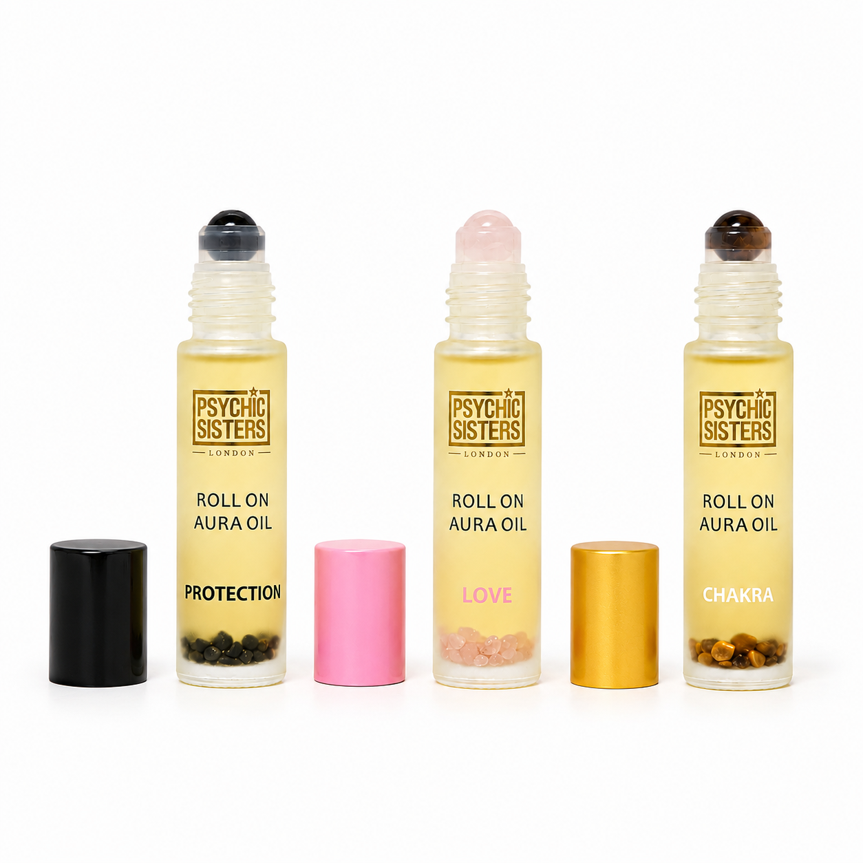 Three Psycho Sisters roll-on aura oil bottles with gold labels and black, pink, and gold caps, arranged on a white background.