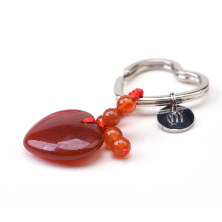 Silver ring with red heart-shaped pendant and beads on a white background