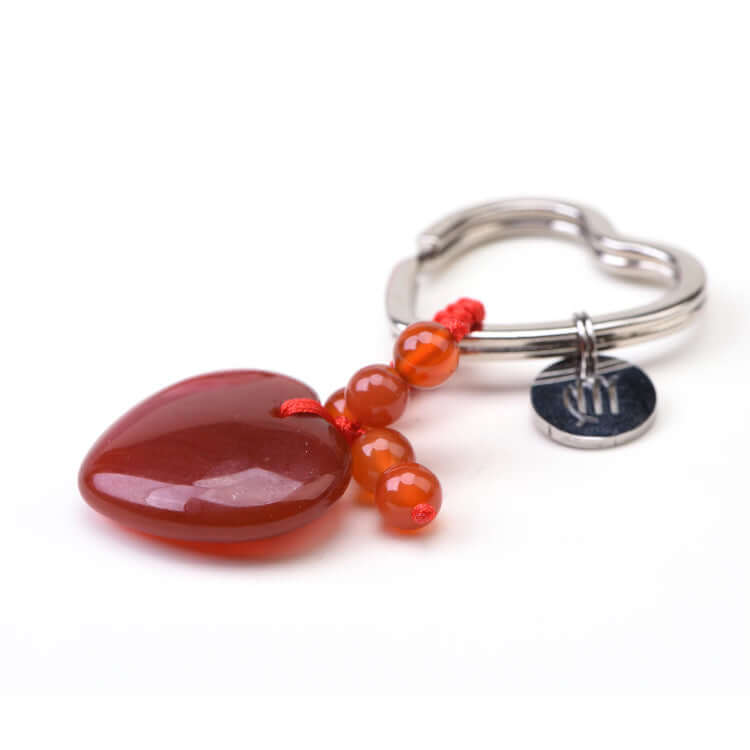 Silver ring with red heart-shaped pendant and beads on a white background