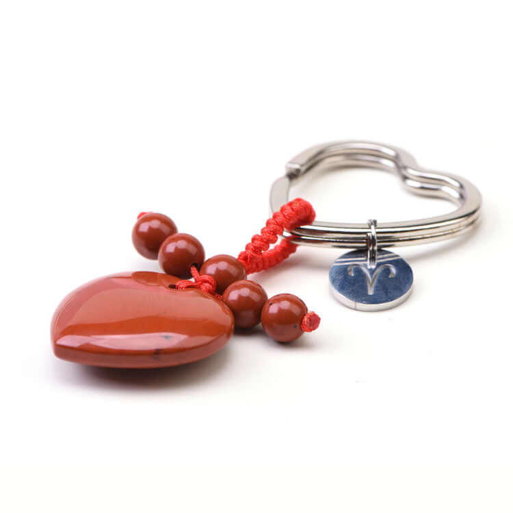 Heart-shaped keychain with red beads and a blue tag on a white background