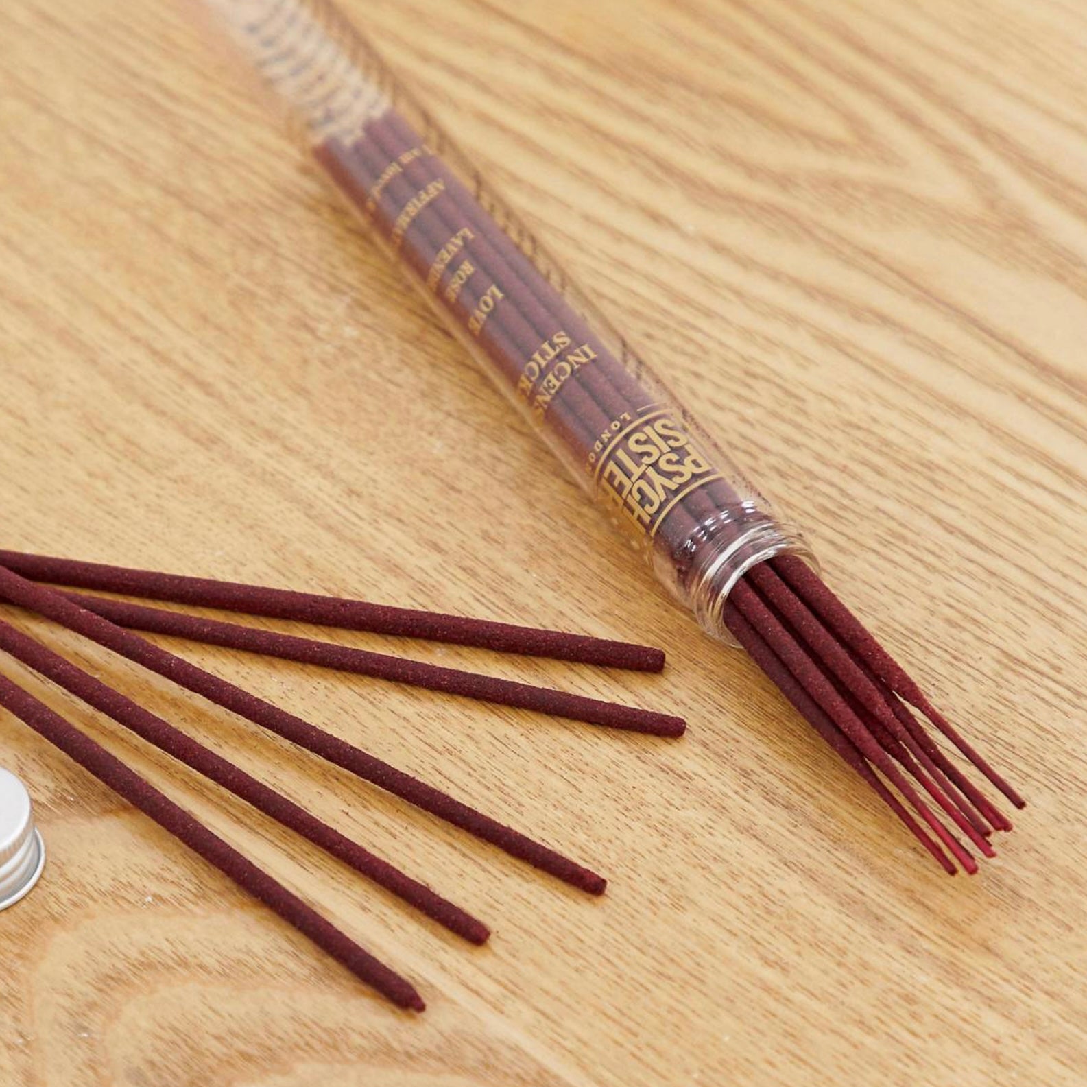 Love Incense sticks displayed in a reusable glass tube on a wooden surface.
