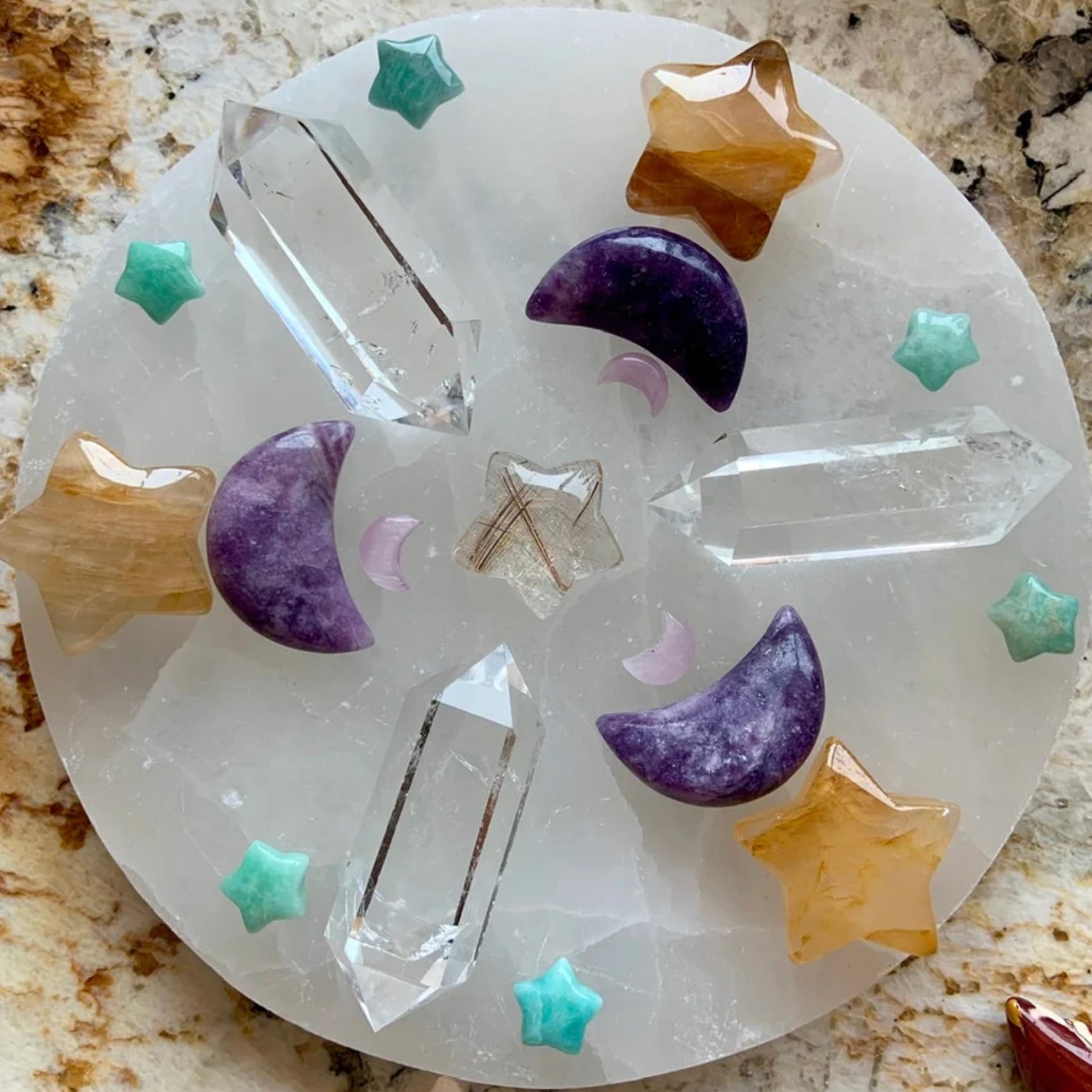 Selenite Charging Plate featuring various crystals including stars and moons for energizing and cleansing.