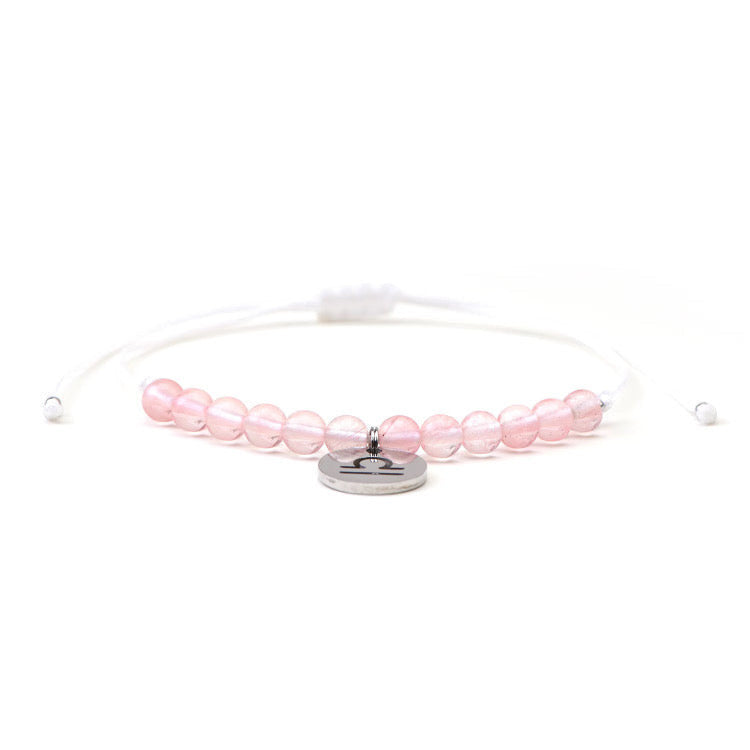 Psychic Sisters Libra zodiac crystal bracelet with pink beads and a silver Libra symbol charm on a white cord