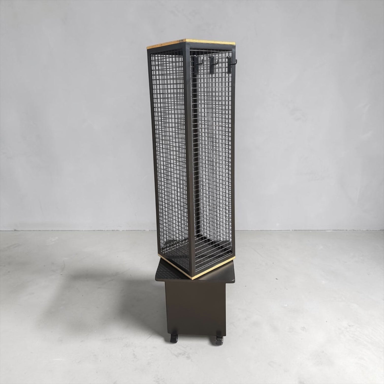 Psychic Sisters 4-sided rotating black mesh spinner display stand with a wooden base and portable castor wheels.
